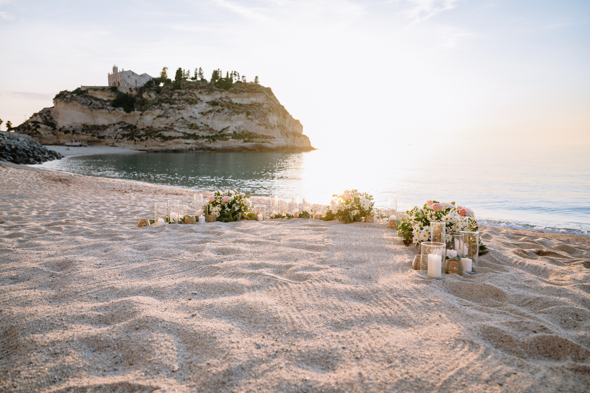 Setup for a surprise beach proposal in Tropea at sunset with Santa Maria dell Isola in the background