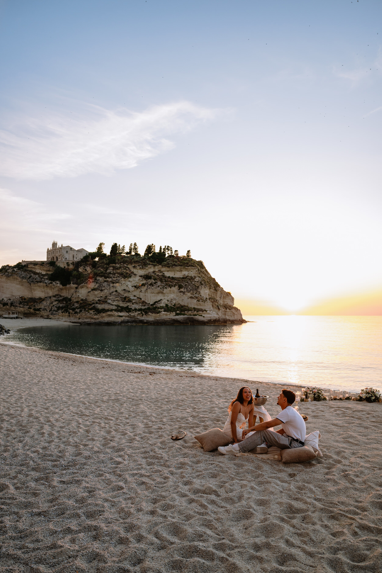 Neutral tones picnic setup with candles and cushions on Tropea beach