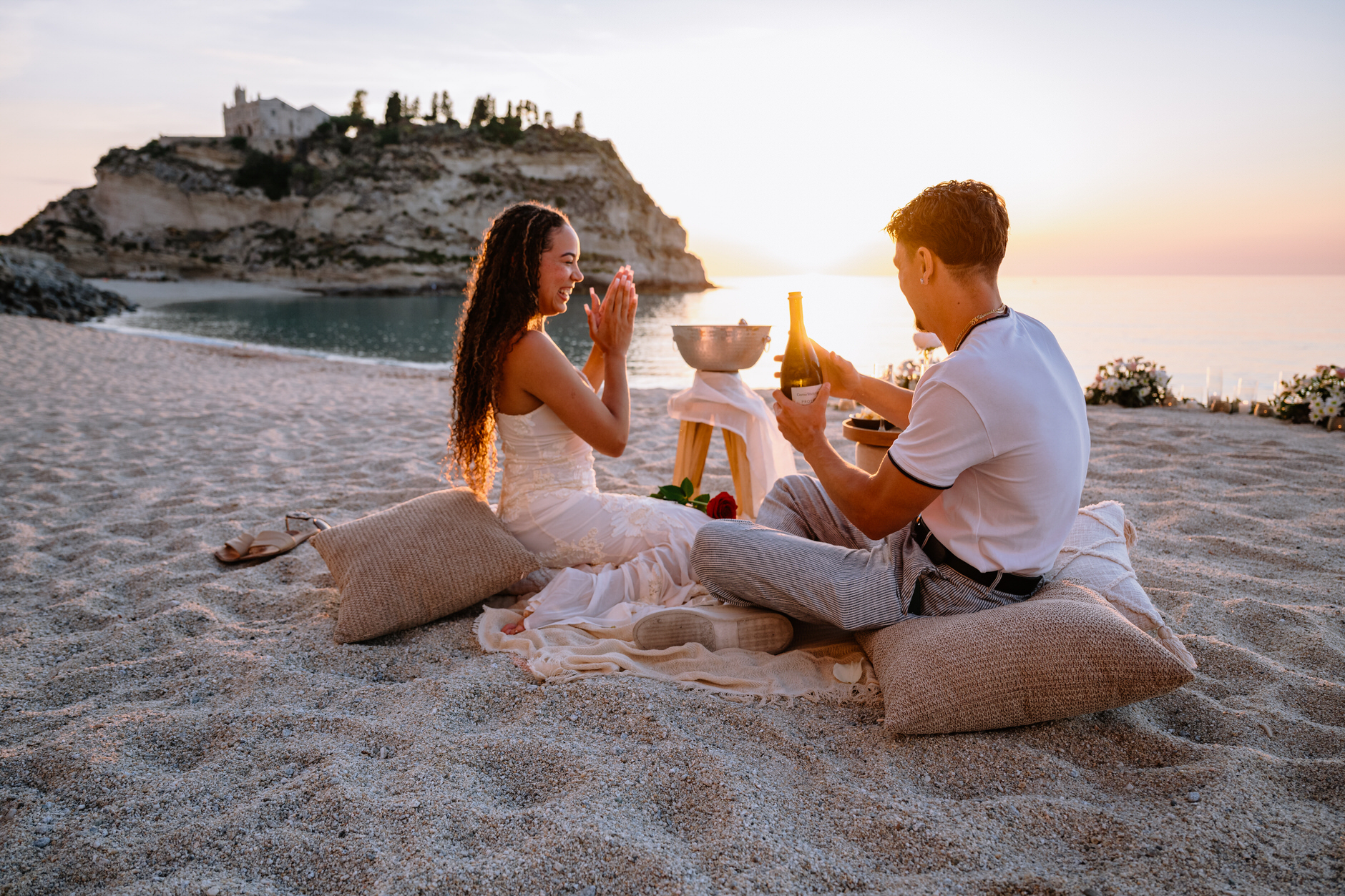 Couple celebrating their engagement with a bottle of champagne on a Tropea beach