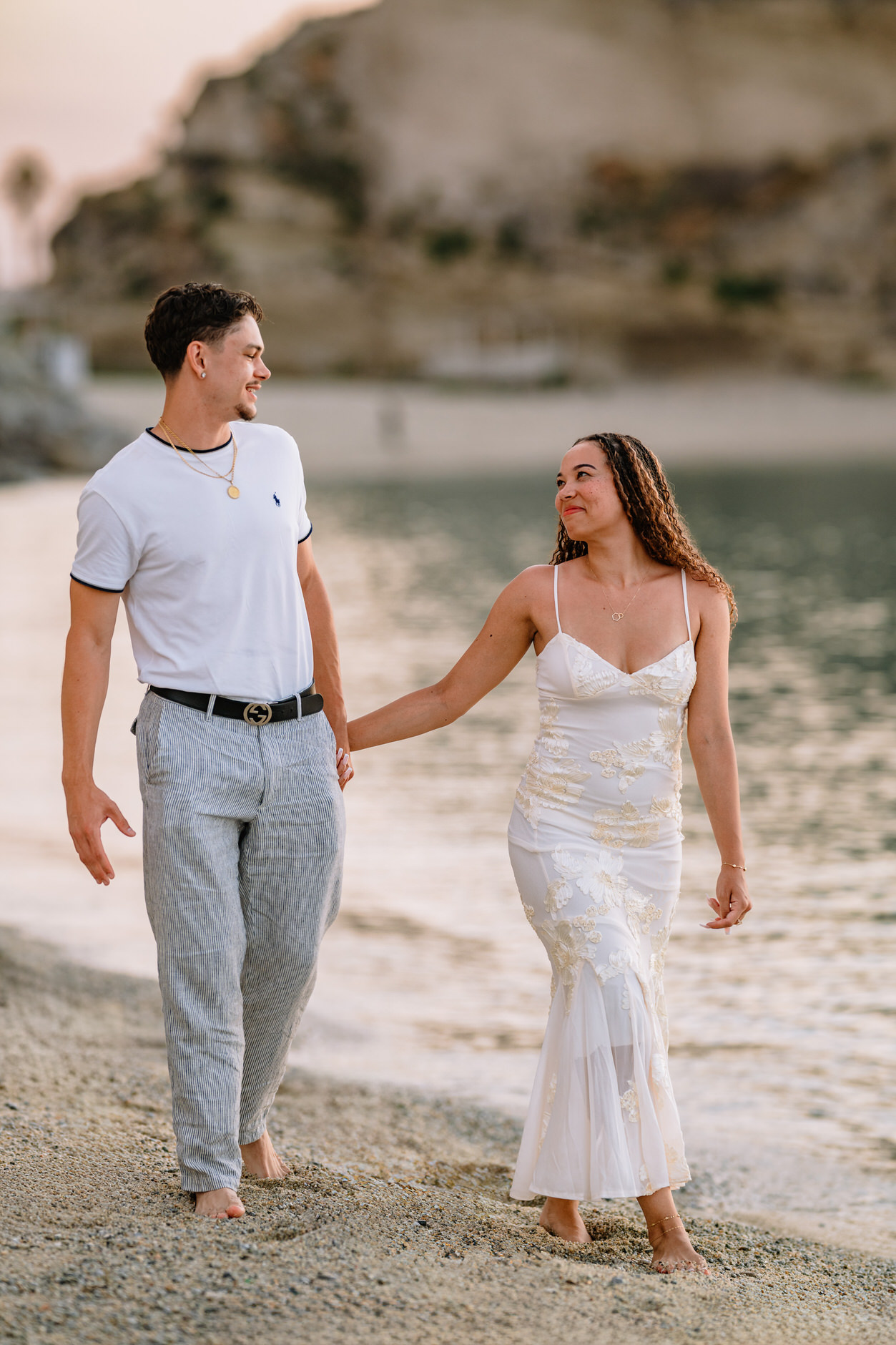 Newly engaged couple embracing on the shoreline in Tropea during golden hour
