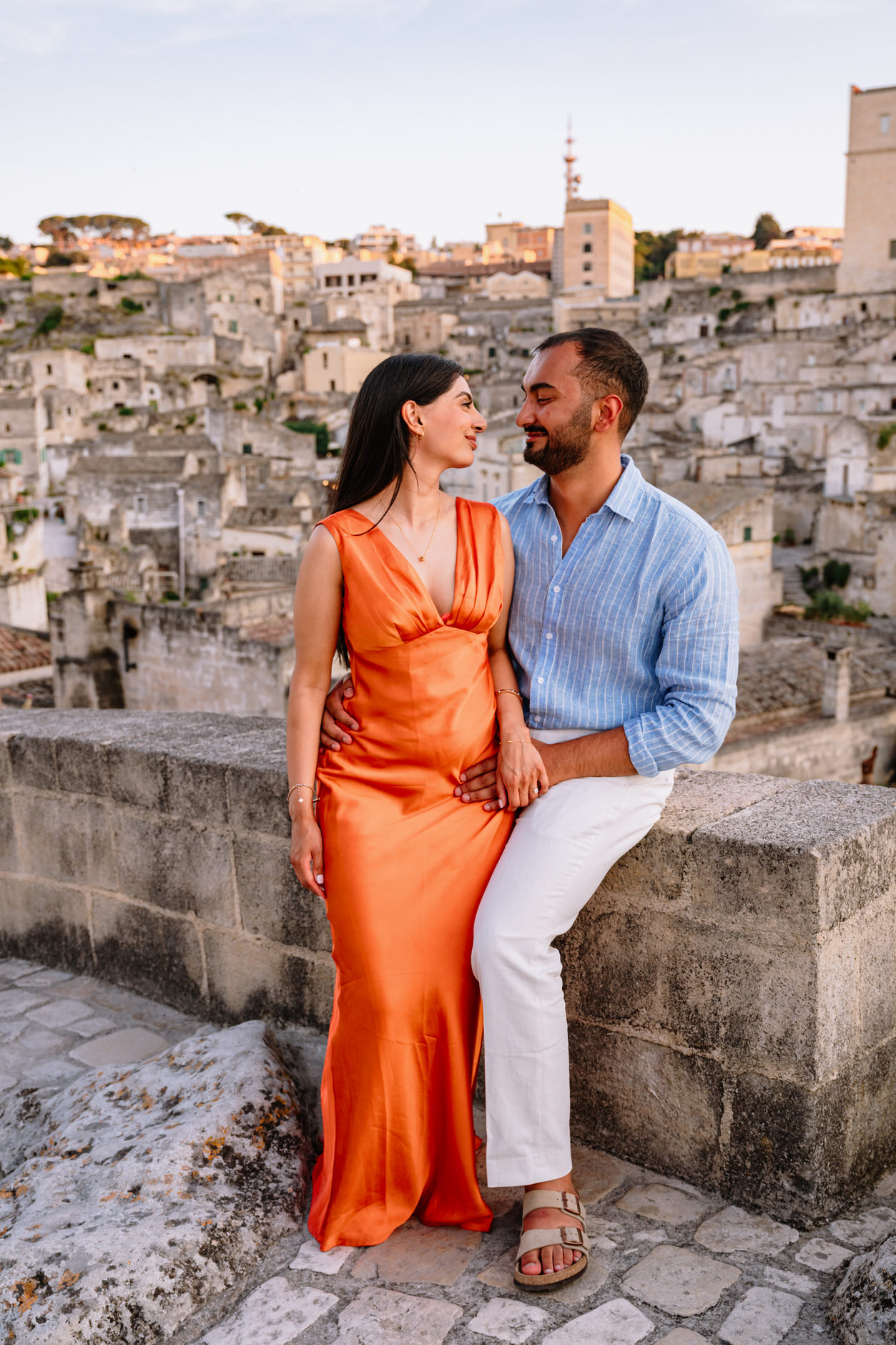 engaged couple looking at each other with matera in the background