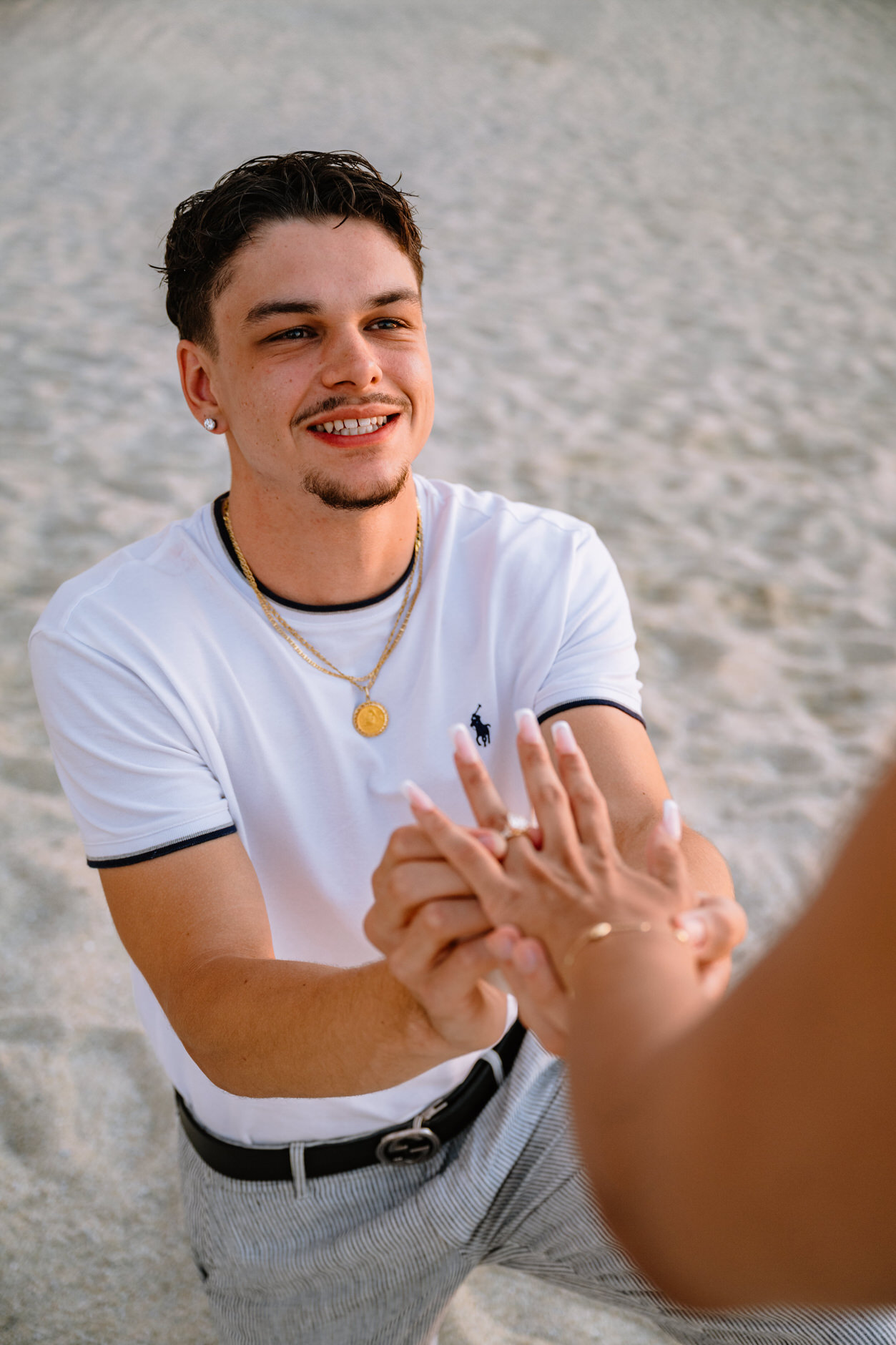 Groom-to-be placing an engagement ring on his fiancee hand on the beach